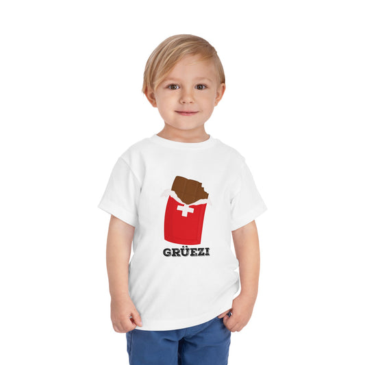 Cute toddler wearing a white Swiss chocolate-themed t-shirt with "Grรผezi" text