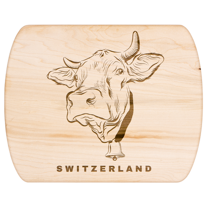 Wooden cutting board featuring Swiss cow engraving, displayed with artisan cheese and bread for authentic Alpine entertaining