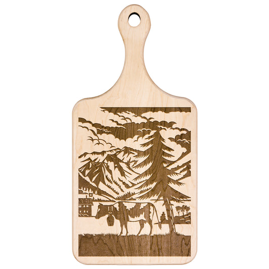 Scherenschnitte cutting board with Swiss cow silhouette against mountain backdrop