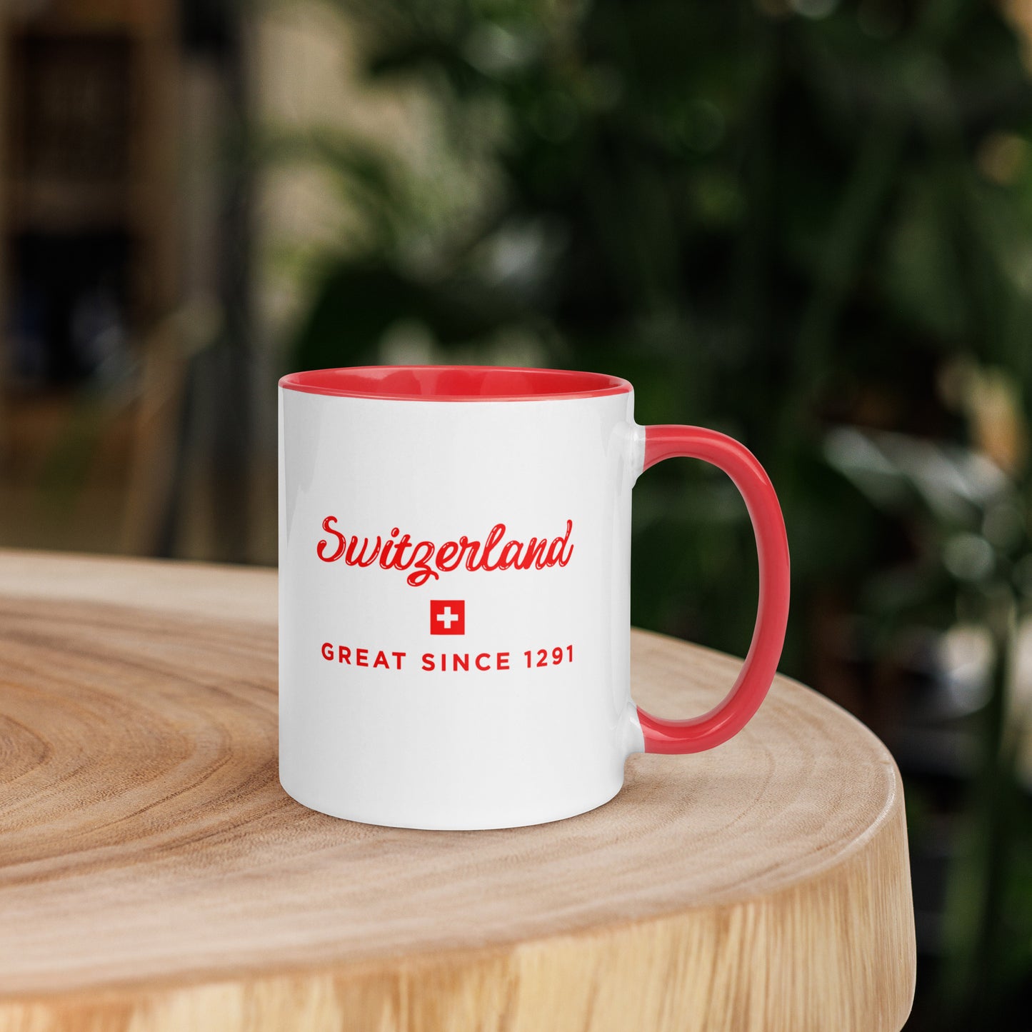 A white ceramic coffee mug with a red handle and red interior, featuring the text 'Switzerland GREAT SINCE 1291' and a small Swiss flag on the front. 