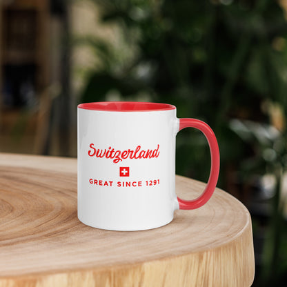 A white ceramic coffee mug with a red handle and red interior, featuring the text 'Switzerland GREAT SINCE 1291' and a small Swiss flag on the front. 