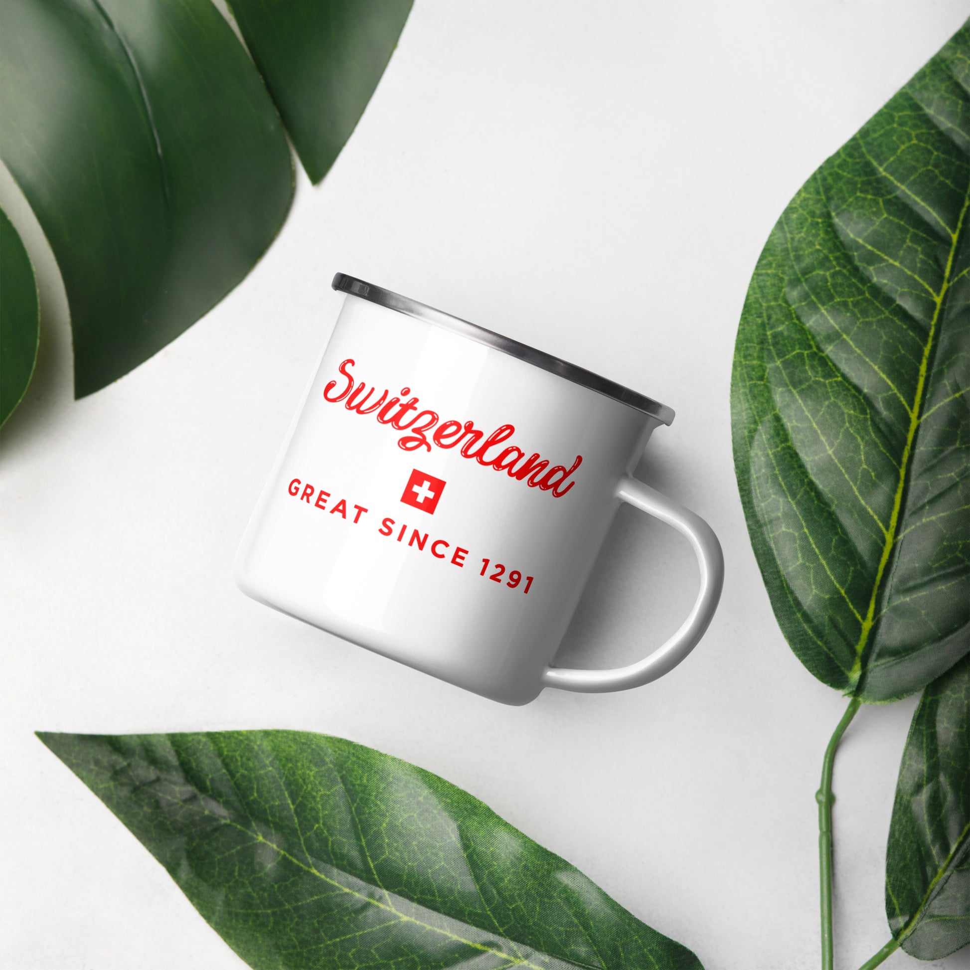 A white enamel-style mug with a silver rim and handle, printed with red 'Switzerland' text, a small Swiss flag, and 'GREAT SINCE 1291' in red. 