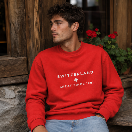 A man wearing a bright red crewneck sweatshirt with white text reading 'SWITZERLAND' and 'GREAT SINCE 1291' 