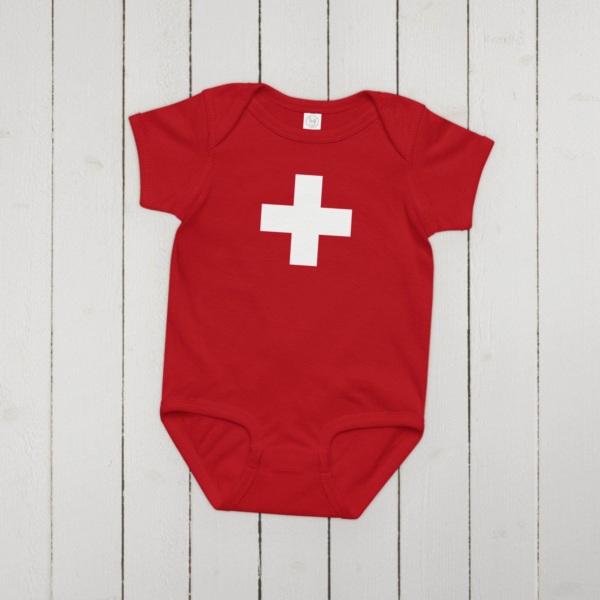red baby onesie featuring bold Swiss cross, premium cotton infant apparel