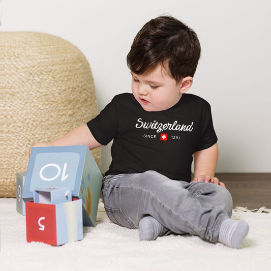 Baby wearing black "Switzerland Since 1291" t-shirt with Swiss flag design.