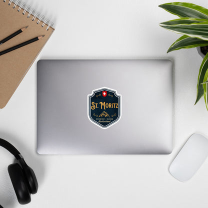 St. Moritz souvenir sticker with gold typography, mountain graphic, and Swiss emblem