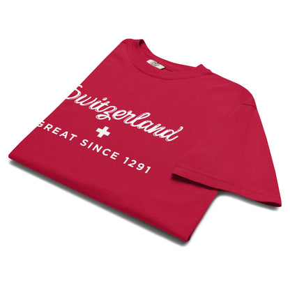 A folded red t-shirt with white graphic text reading 'Switzerland GREAT SINCE 1291' and a white cross